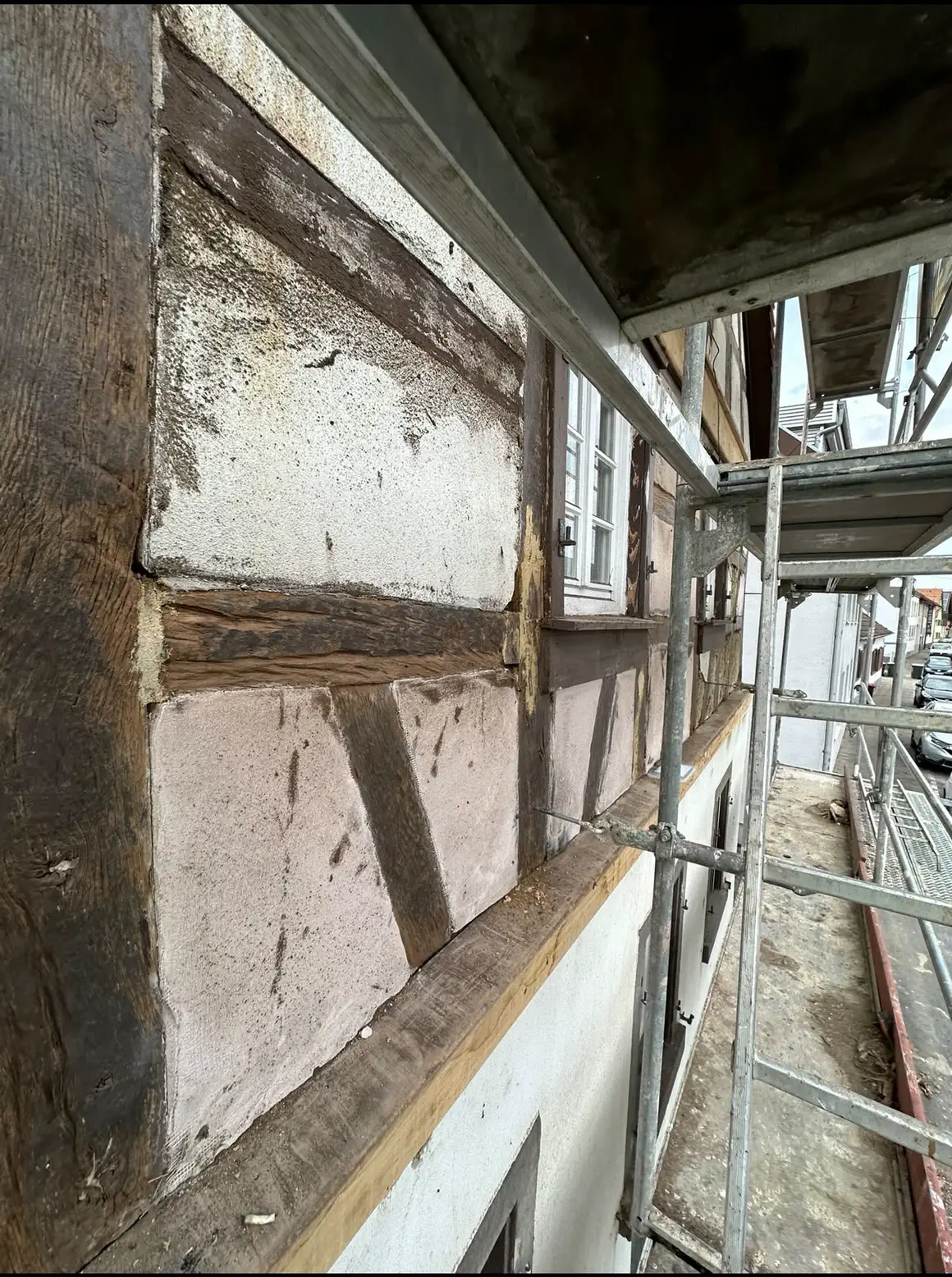 Fassadendetail mit altem Balkenwerk und teilweise abgetragenem Putz während der Sanierung