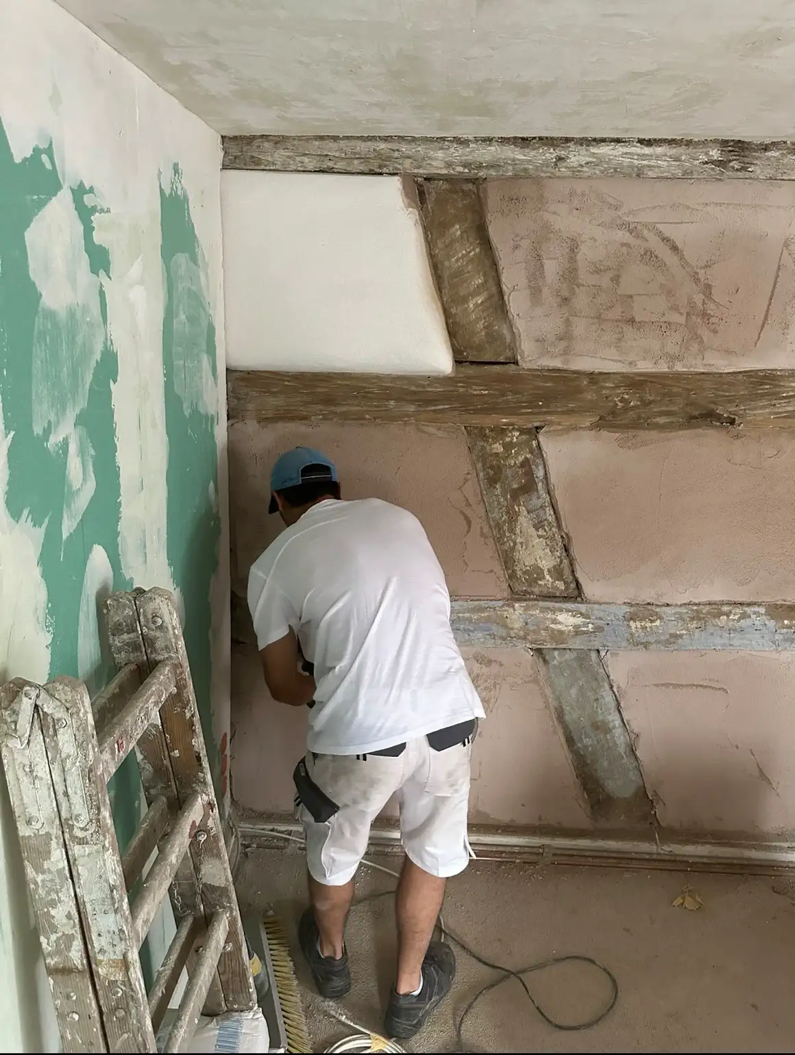 Maler beim Vorstreichen der Wandflächen zwischen dem Fachwerk im Obergeschoss