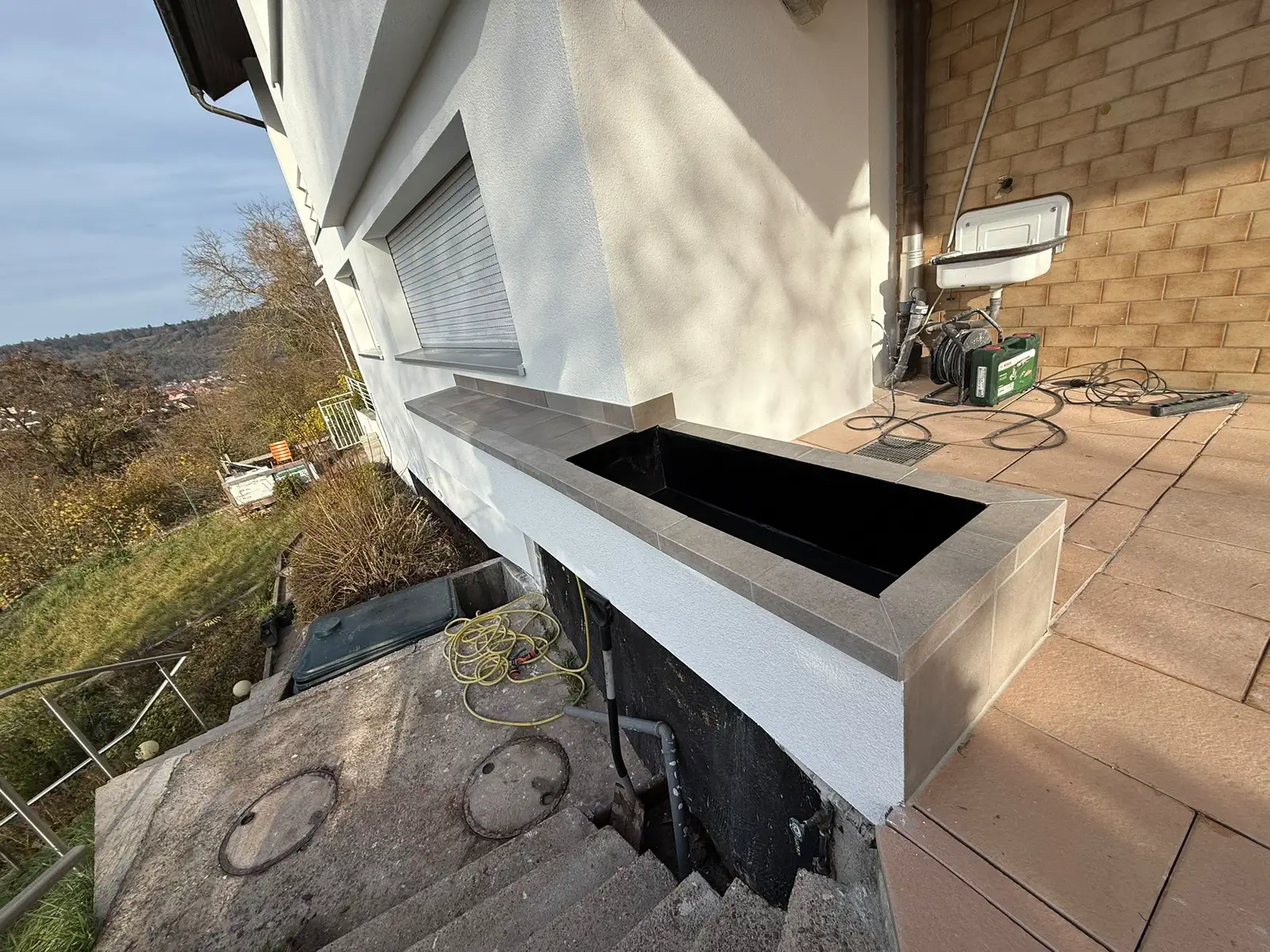 Blumentrog an der Hausfassade mit neu verlegten Platten, seitliche Ansicht
