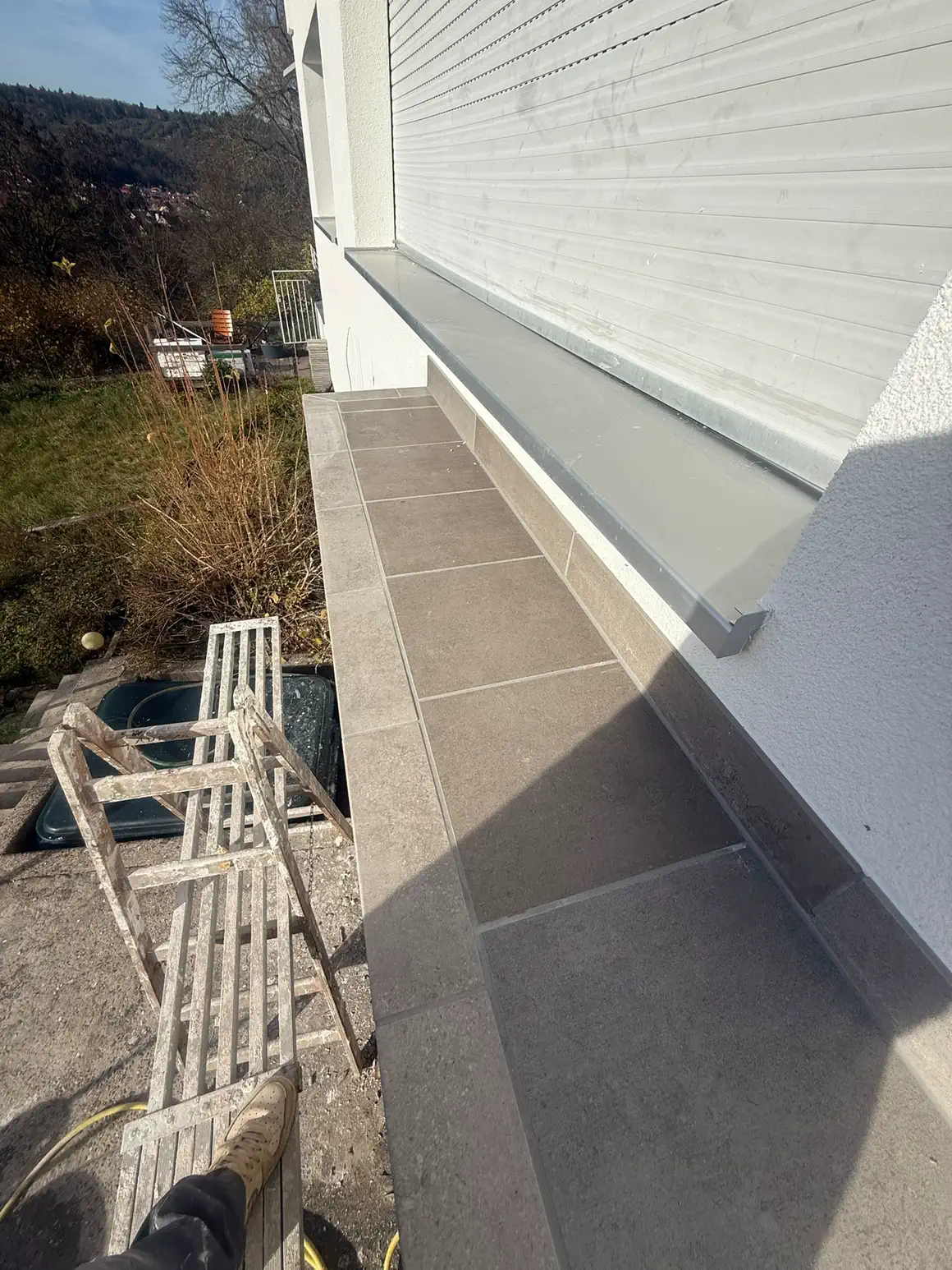 Seitenansicht des fertigen Plattenbelags am Blumentrog entlang der Fassade